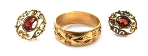 9ct gold jewellery, comprising a gold wedding band of etched floral design, size K&frac12;, a pair of garnet and gold framed stud earrings, with later backs, 4.1g all in.