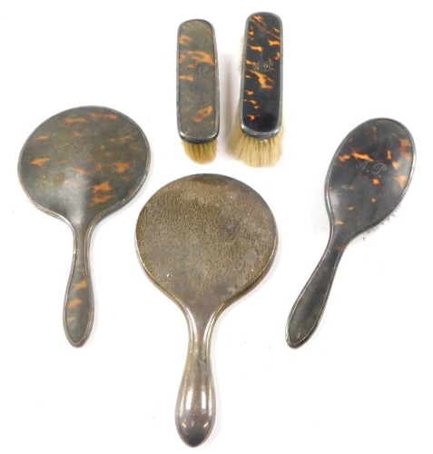 A George V silver and tortoiseshell four piece dressing set, monogrammed AP, comprising hand mirrors, and three brushes, Birmingham 1925, and a George VI silver backed hand mirror, Birmingham 1946..