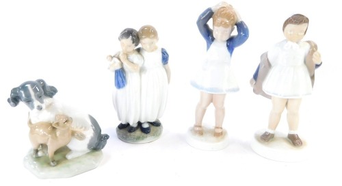 Four porcelain figure groups, comprising a Nao cat and dog, Bing & Grondahl girl with coat, no 2387, and girl tying hair, no 2381, and a Royal Copenhagen group of two girls with dolls, no 939, the tallest 21cm high.