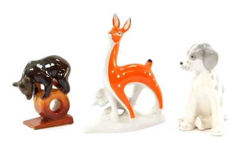 Three USSR porcelain figures, comprising a Lomonosov dog seated, 17cm high, an orange deer, 22cm high, and a bear on a wheel, 14cm high. (3)