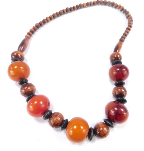 An amber and wooden beaded necklace, with five amber beads, each approx 2.5cm wide, on string strand with wooden bead breaks, 101g all in.