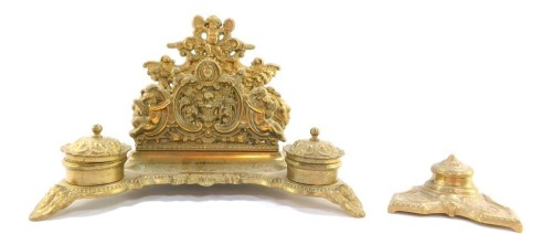 A 19thC brass desk stand, with two splay letter rack back and cherub emblems, with two ink wells, together with a loose ink well with scarab detail, 20cm and 23cm high, smaller ink well 11cm wide. (2)