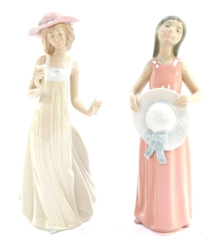 A Lladro figure of a girl in pink dress with sun hat, 26cm high, and a Nao figure of a lady in cream dress carrying flower, 26cm high. (2)