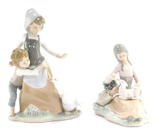 Two Lladro figure groups, comprising a girl feeing a lamb, 17cm high, and a mother and boy with goose, 24cm high. (2)
