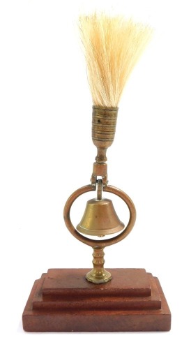 A late 20thC brass fly terret ringing bell, on a stepped wooden base, 23cm high.