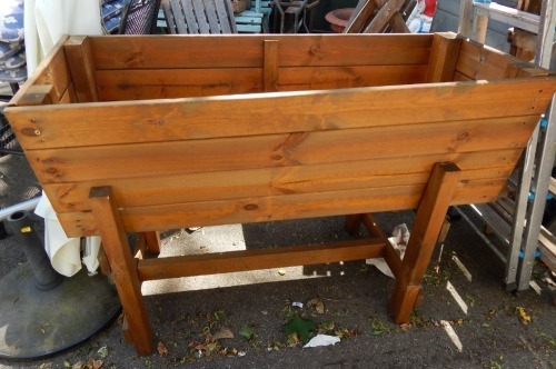 A modern raised wooden planter, on a trestle base, 81cm high, 120cm wide, 51cm deep.