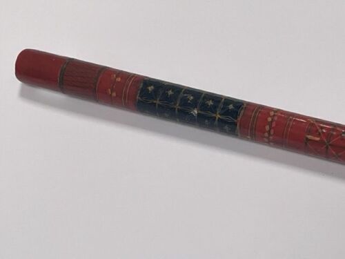 An Indian early 20thC red and black lacquer walking cane, with bands of geometric decoration, 93cm wide.