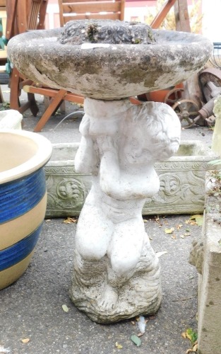 A painted figural concrete bird bath, the circular bath raised on a figure of a putto, 61cm high, 35cm wide, together with a reconstituted stone sundial, the brass dial marked 'Morning Glory', 32cm high, 23cm wide. (2)