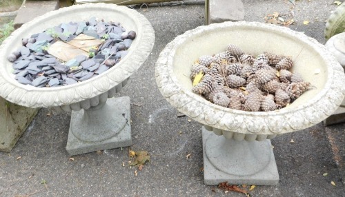 A pair of reconstituted stone planters, each with a fluted leaf top, on square base, 44cm high, 57cm diameter.