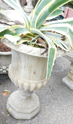 A reconstituted stone urn, of large proportions, with a flared a bulbous stemmed top, on an octagonal base, 76cm high, 56cm diameter.