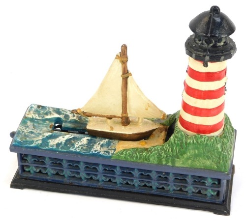 A novelty cast money box, formed as a lighthouse and boat, 20cm high.