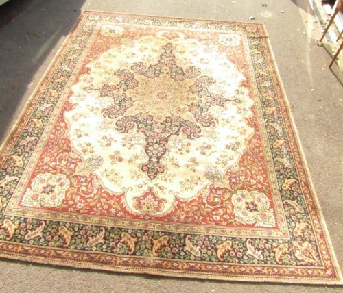 An English Caucasian style rug, the central shaped medallion decorated with flowers and scrolling leaves against a blue ground, within a floral red cream and blue border, 362cm x 273cm.