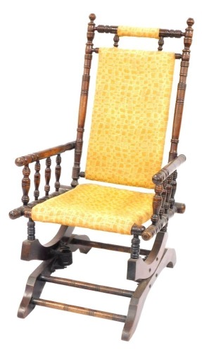 An American rocking chair, with bobbin turned supports, on a yellow boxed design upholstered seat and back, 108cm high, 55cm wide, 49cm deep.