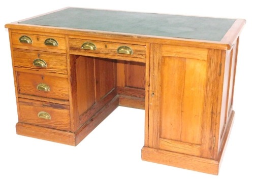A Victorian pitch pine kneehole desk, with green leather inset top, above an arrangement of four short drawers, one long drawer and a cupboard, 75cm high, 132cm wide, 75cm deep.