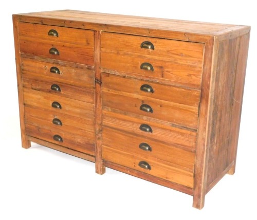 An industrial pine sideboard, with front arrangement of drawers and two cupboards, formed from printers drawers, 90cm high, 134cm wide, 50cm deep.