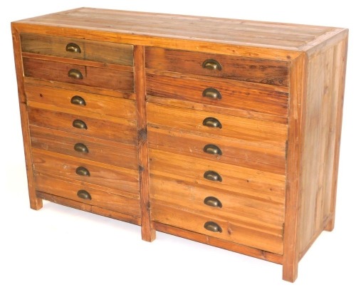 An industrial pine sideboard, with front arrangement of drawers and two cupboards, formed from printers drawers, 90cm high, 134cm wide, 50cm deep.