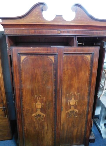 An Edwardian mahogany and marquetry double wardrobe, with swan neck pediment cornice above two panelled doors, on bracket feet, 220cm high, 140cm wide, 50cm deep.