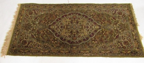 A Persian rug, green ground with a central floral medallion, against a floral ground on repeating floral border, 178cm x 90cm.