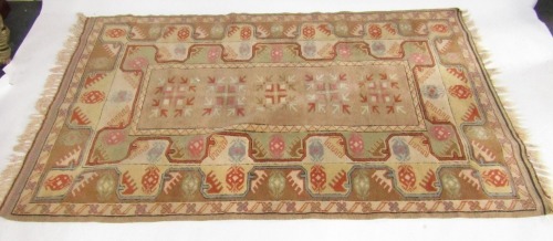 A Turkish rug, peach and cream ground, the central rectangular field decorated with five floral medallions, within repeating borders of flowers and animals, 200cm x 127cm.